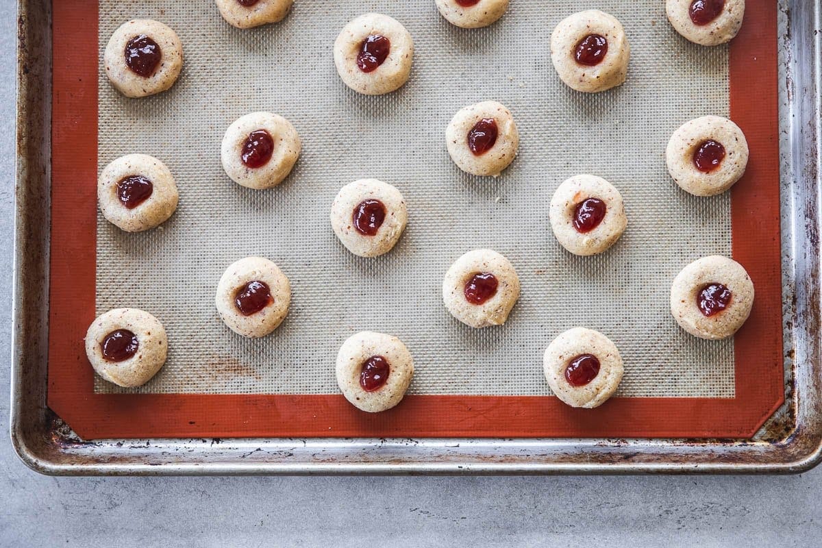 Fill the indent of each cookie with a quarter teaspoon of strawberry jam and bake.