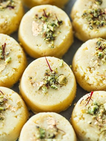 Malai Peda (Indian Milk Fudge) garnished with pistachio, saffron and gold leaf.