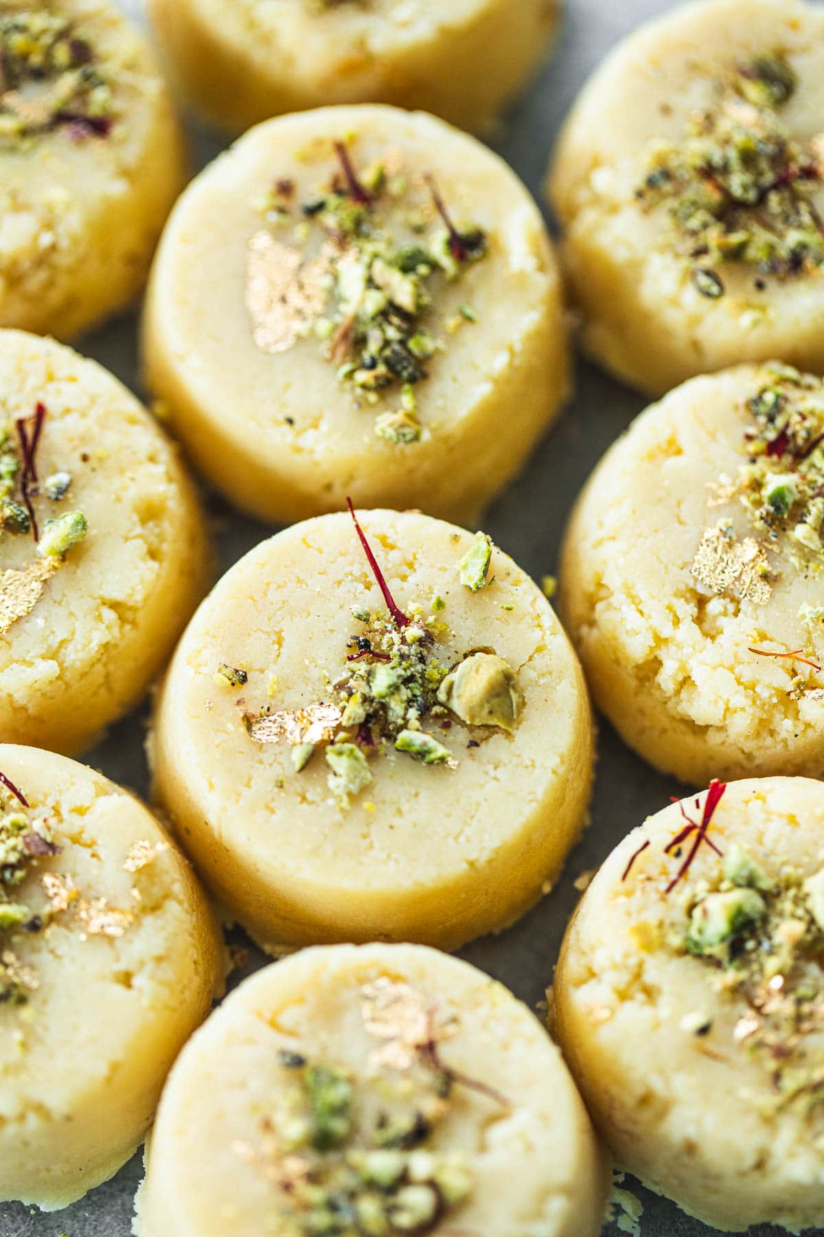 Malai Peda (Indian Milk Fudge) garnished with pistachio, saffron and gold leaf.