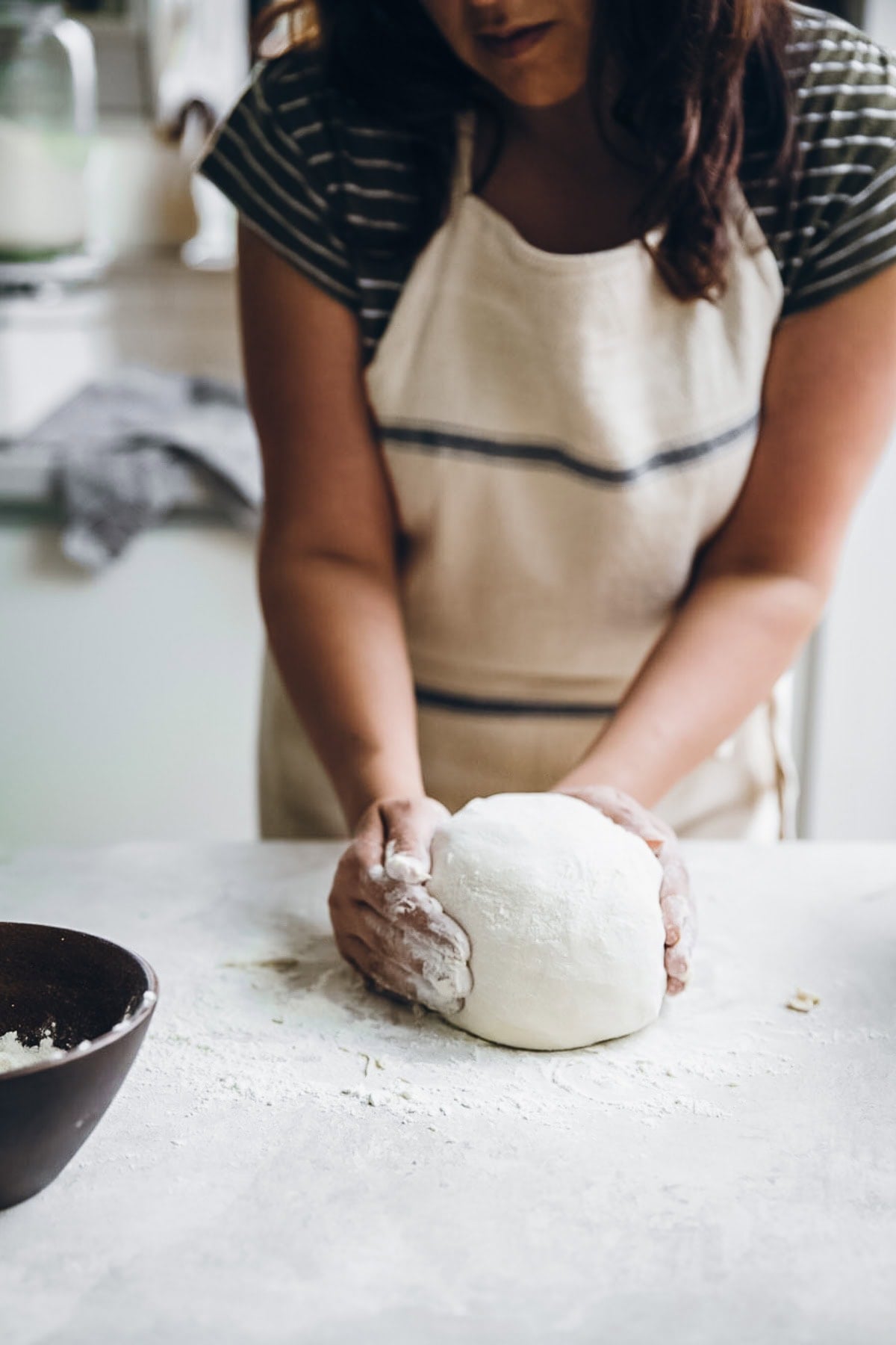 Kneading the pizza dough into a smooth ball.