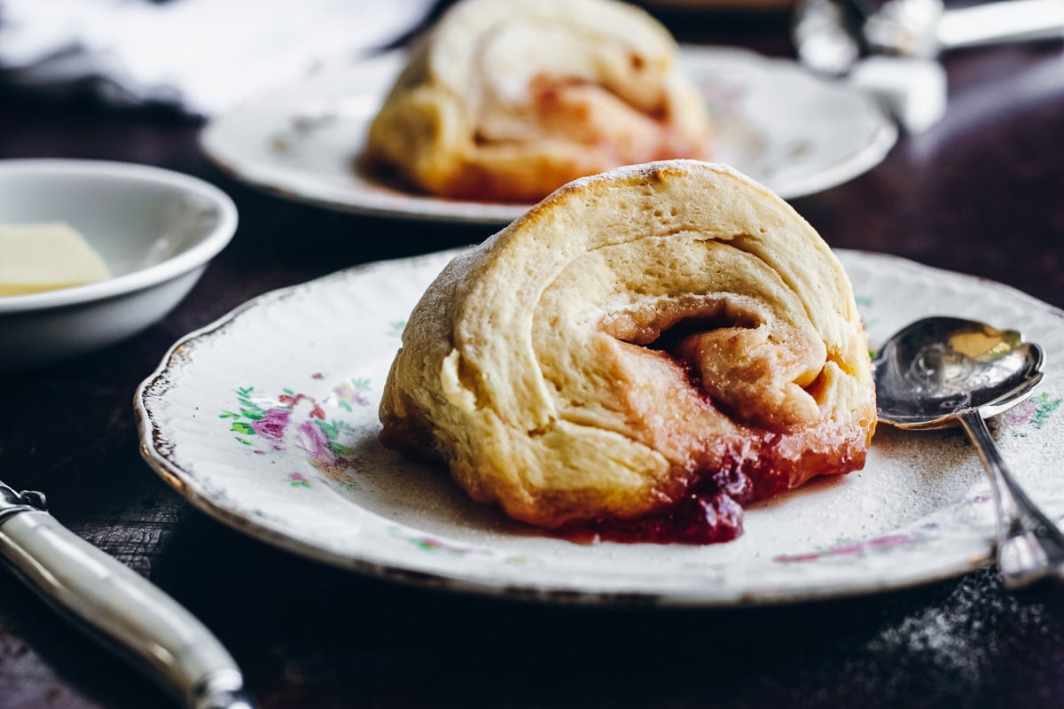 Sticky pinwheel jam scones served with fresh cream and tea.