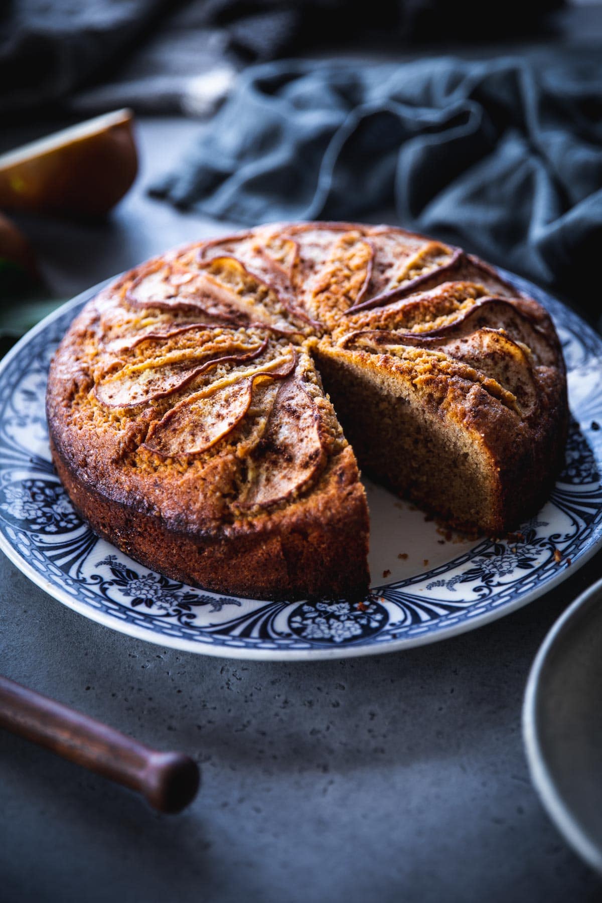 Pear Cake served on a floral blue plate with a slice cut out.