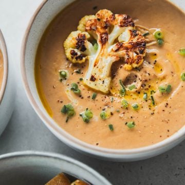 Roasted Cauliflower Soup in a bowl with cauliflower floret garnish and toasted bread.