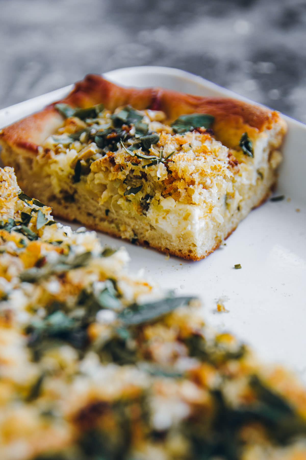 A square slice of Roasted Cauliflower Grandma Pie in a white tray.