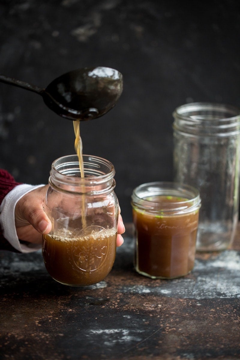 Mushroom Broth being ladled into a glass jar.