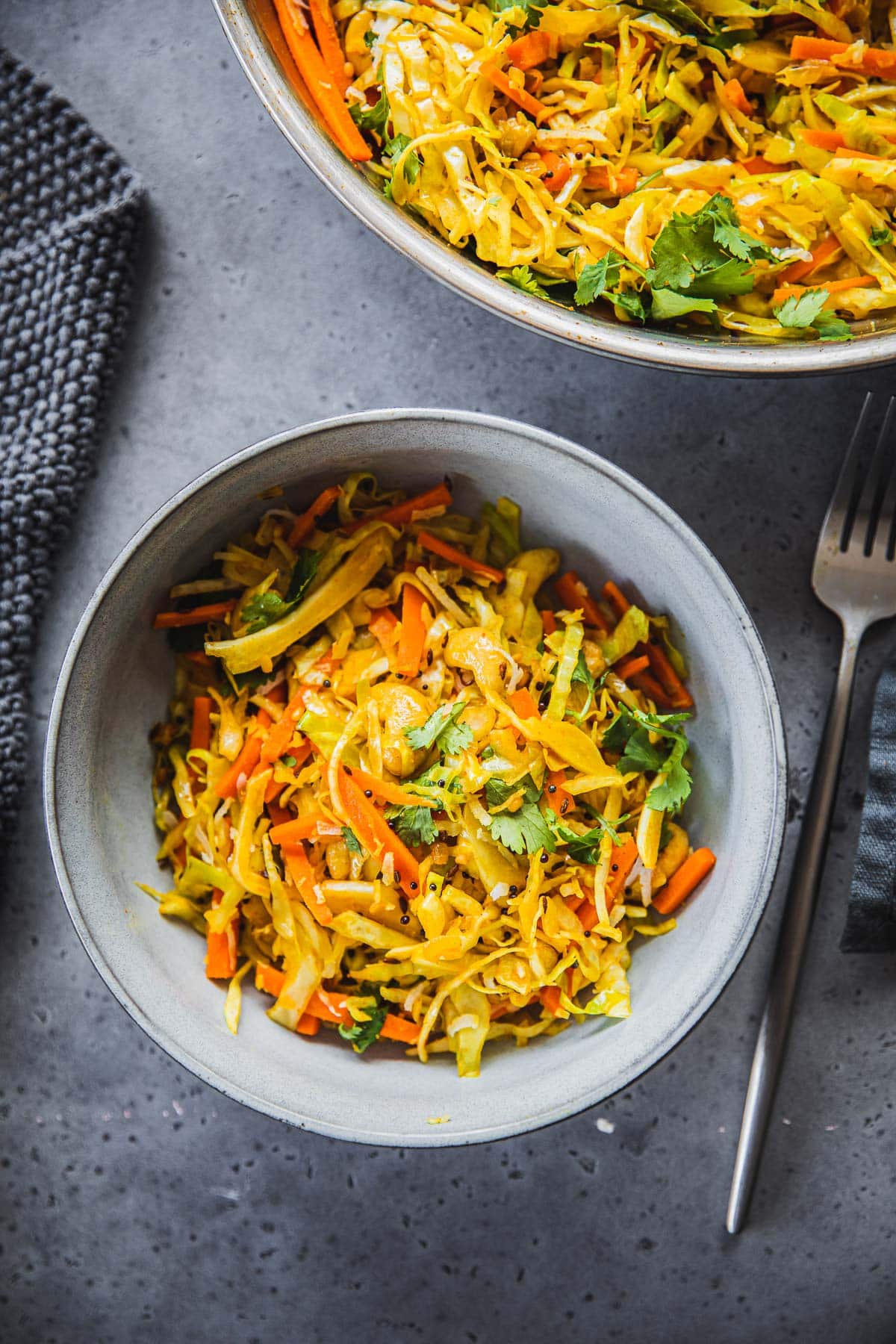 Cabbage Thoran in a frying pan and served in a bowl along with a fork and napkin.