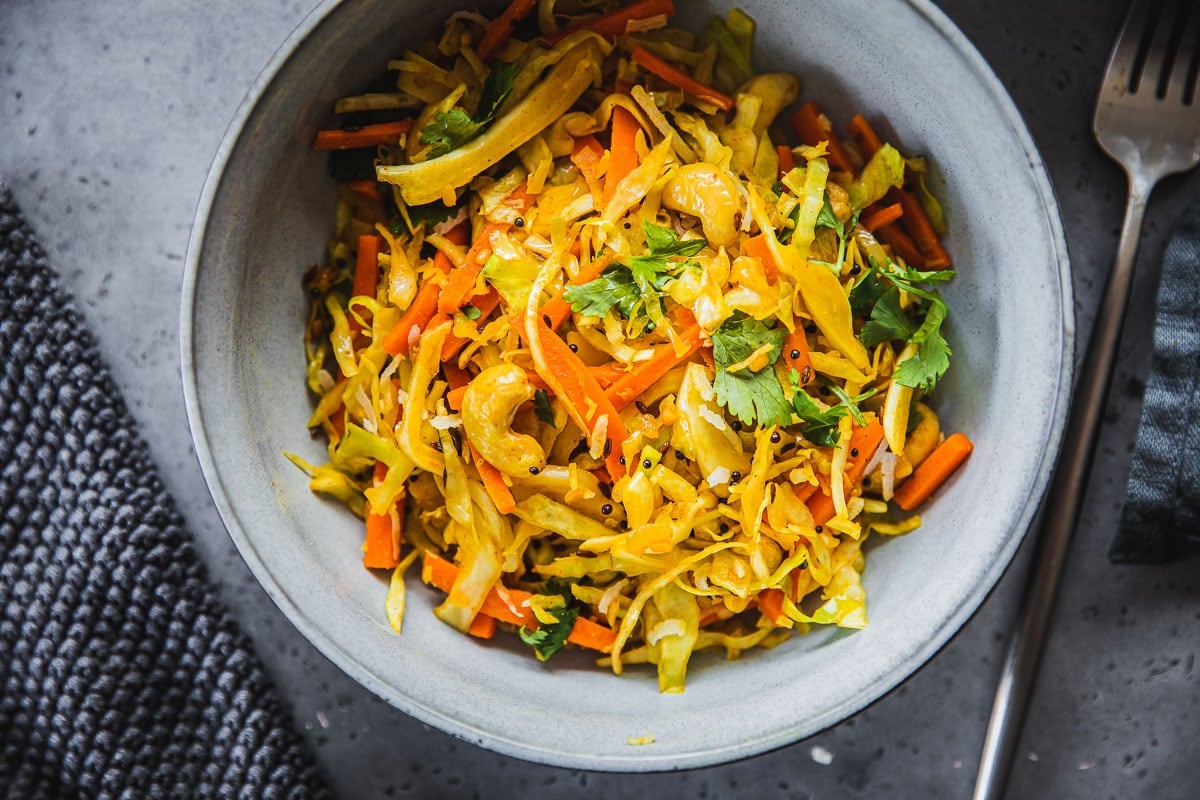 Cabbage Thoran served in a bowl with a fork and napkin on the side.