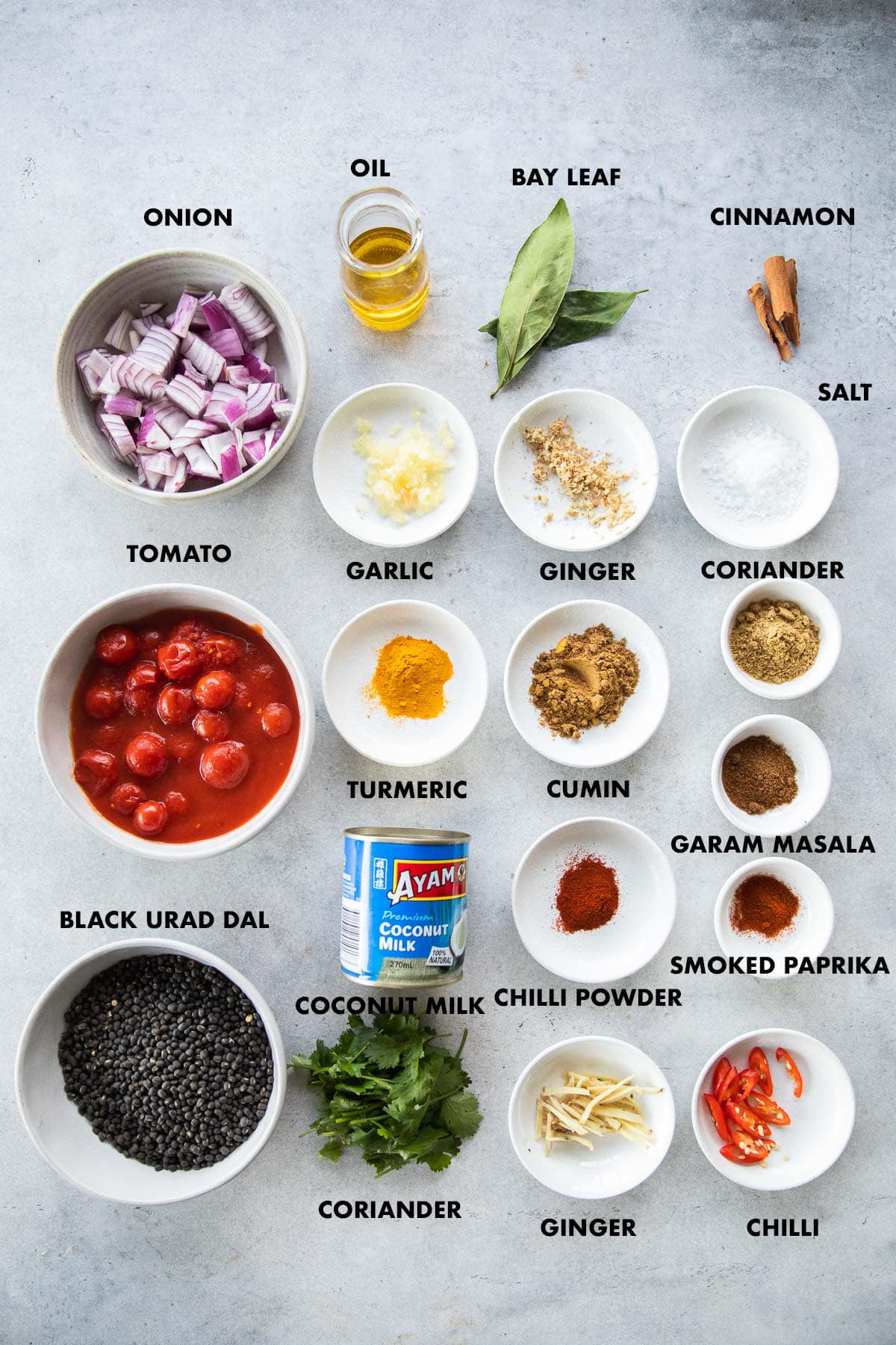 Vegan Dal Makhani ingredients labeled - onion, tomato, ginger, garlic, black urad dal, coconut milk, oil, bay leaf, cinnamon, turmeric, cumin, coriander, garam masala, chilli powder, smoked paprika and salt.