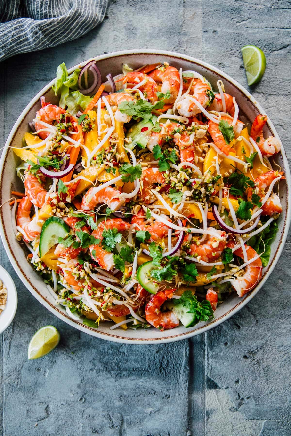 Thai Prawn Mango Salad in a serving bowl with lime wedges.