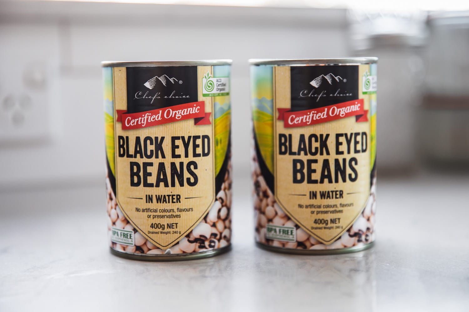 Two cans of Black-eyed peas on a kitchen counter