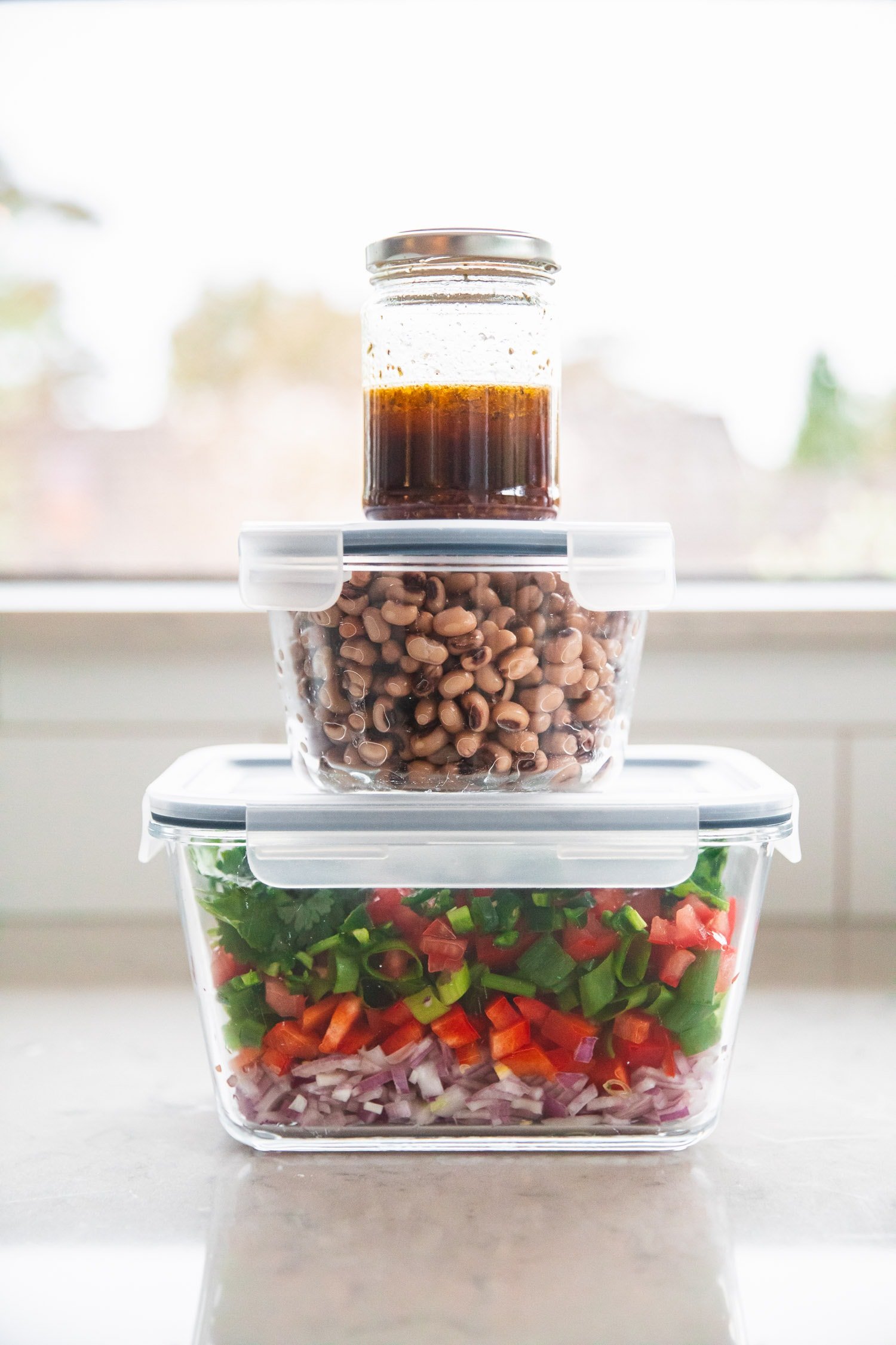 Meal prep Texas Caviar recipe with dressing, cooked black eyed peas and chopped veggies and herbs in separate containers