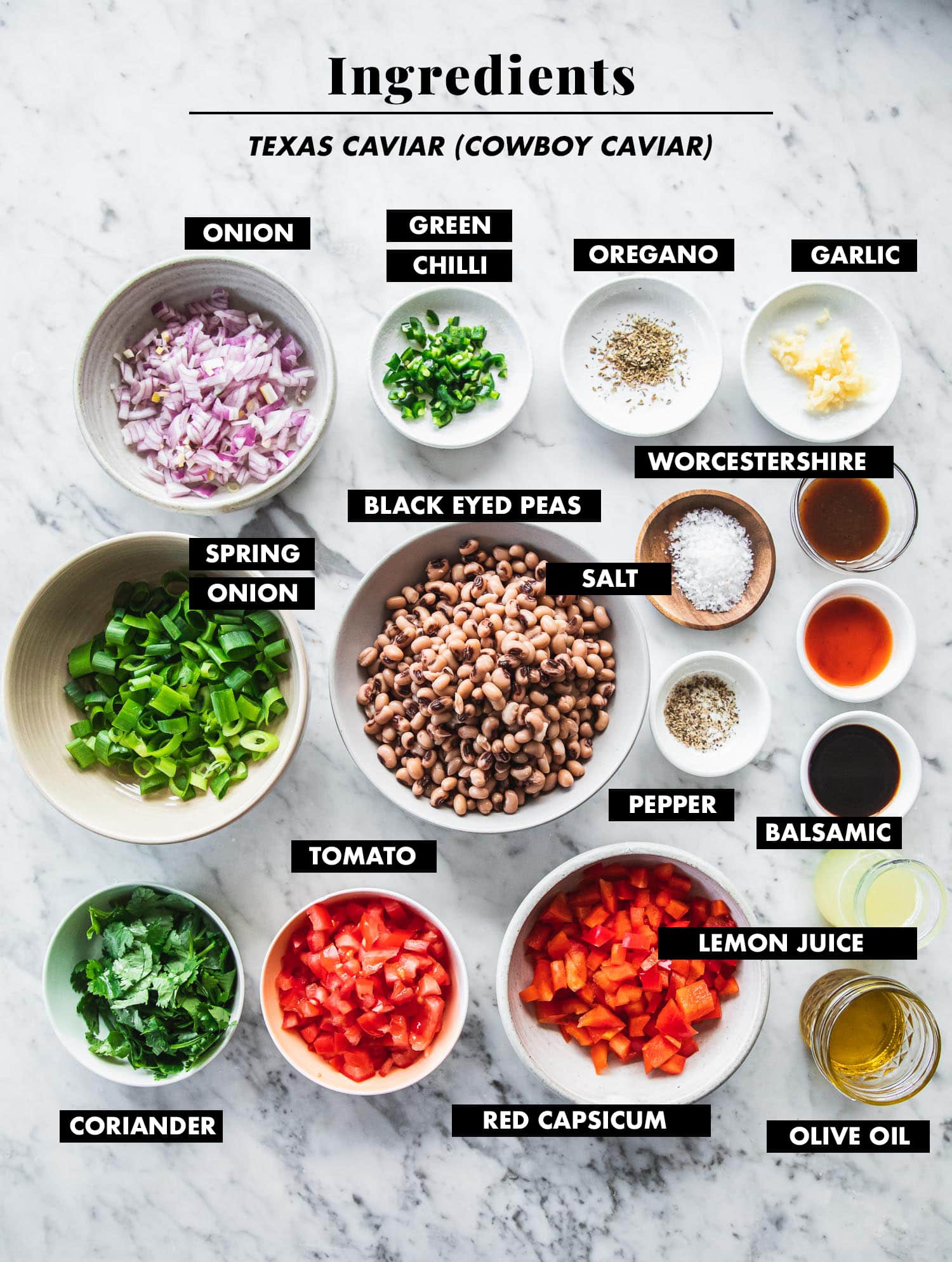 Ingredients for Texas Caviar (Cowboy Caviar Salad) measured out in bowls and laid out on a marble tabletop - onion, tomato, capsicum, cooked black eyed peas, spring onion, coriander, chilli, oregano, garlic, olive oil, lemon juice, balsamic vinegar, Tabasco sauce, Worcestershire sauce, salt and pepper