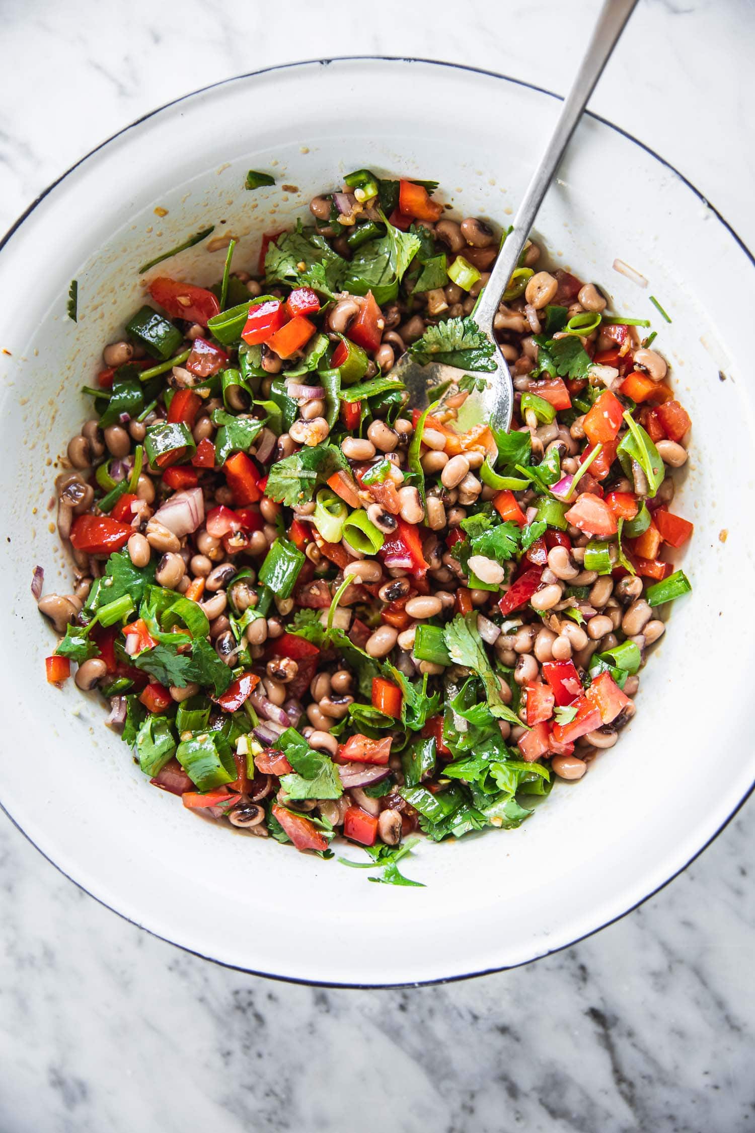 Fully assembled Texas Caviar in a bowl made with black eyed peas, chopped salad veggies, chilli, coriander and a zesty lemony dressing spiked with Tabasco sauce.