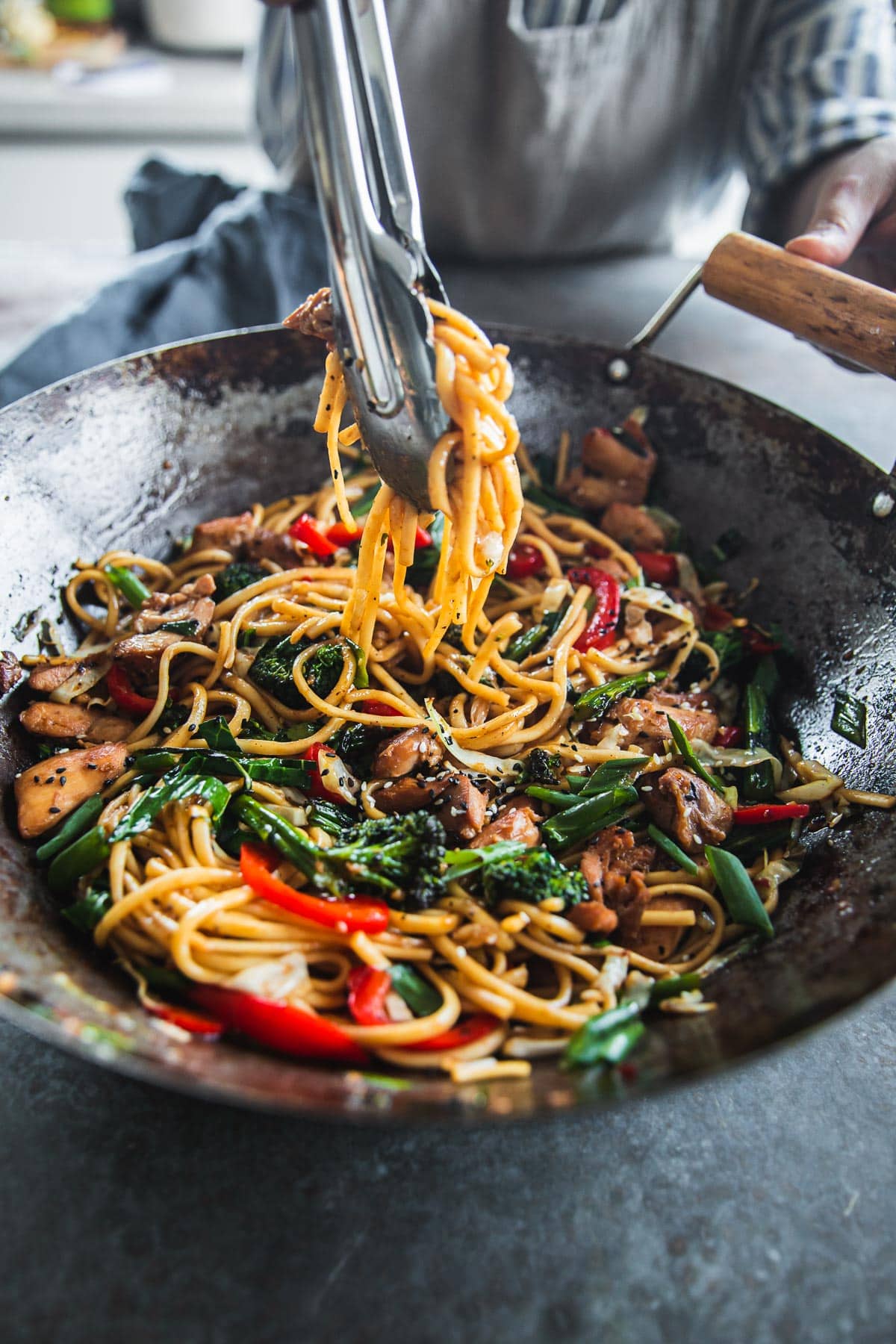 Toss Chicken Udon Noodles in the wok with metal tongs before serving.