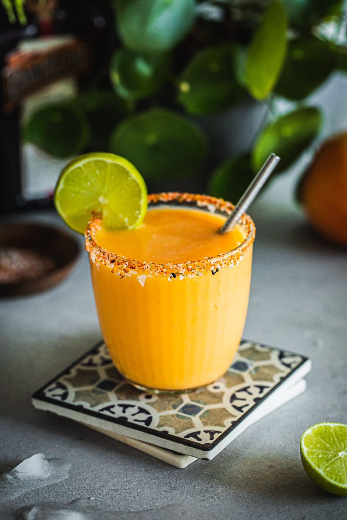 Mango Margarita served in a tumbler with a chilli salt rim and lime wheel and steel straw.