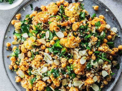 Roasted Cauliflower Salad With Chickpeas And Quinoa served in a salad platter with extra parsley and almond flakes on the side.