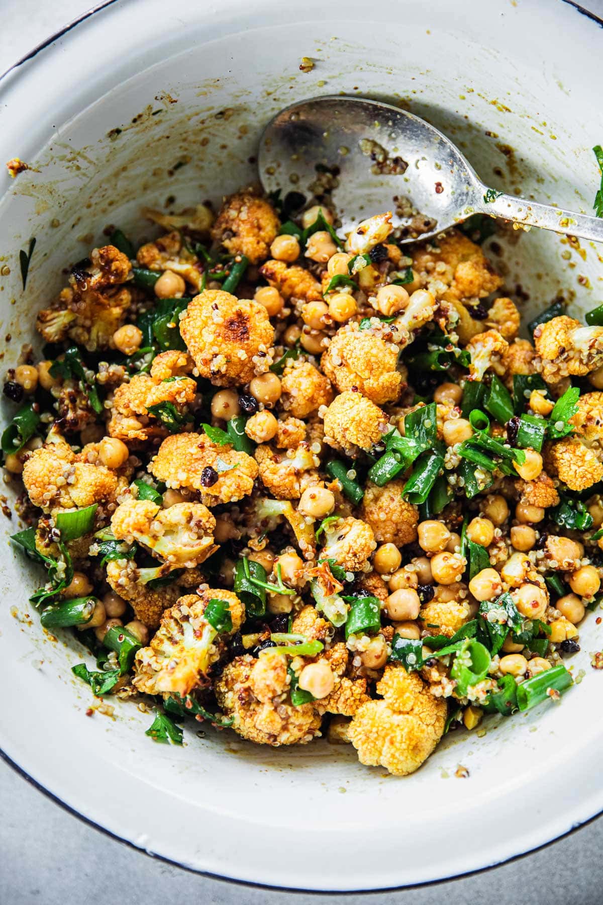 Roasted Cauliflower Salad. With Chickpeas and Quinoa mixed in a large bowl with salad dressing.