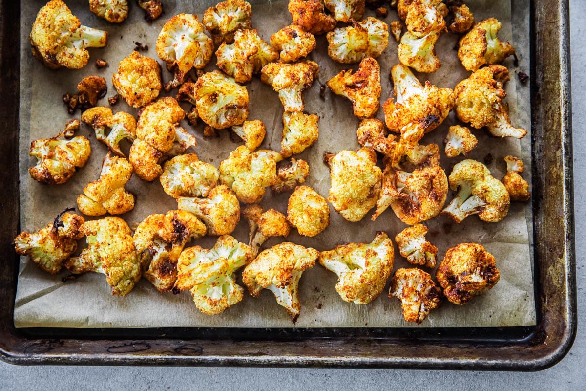 Golden roasted cauliflower, cooling on a baking tray after roasting in the oven.