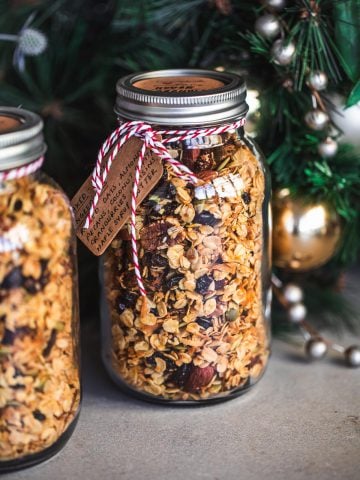 Homemade Granola stored in glass jars with twine and a handwritten label for gifting at Christmas.