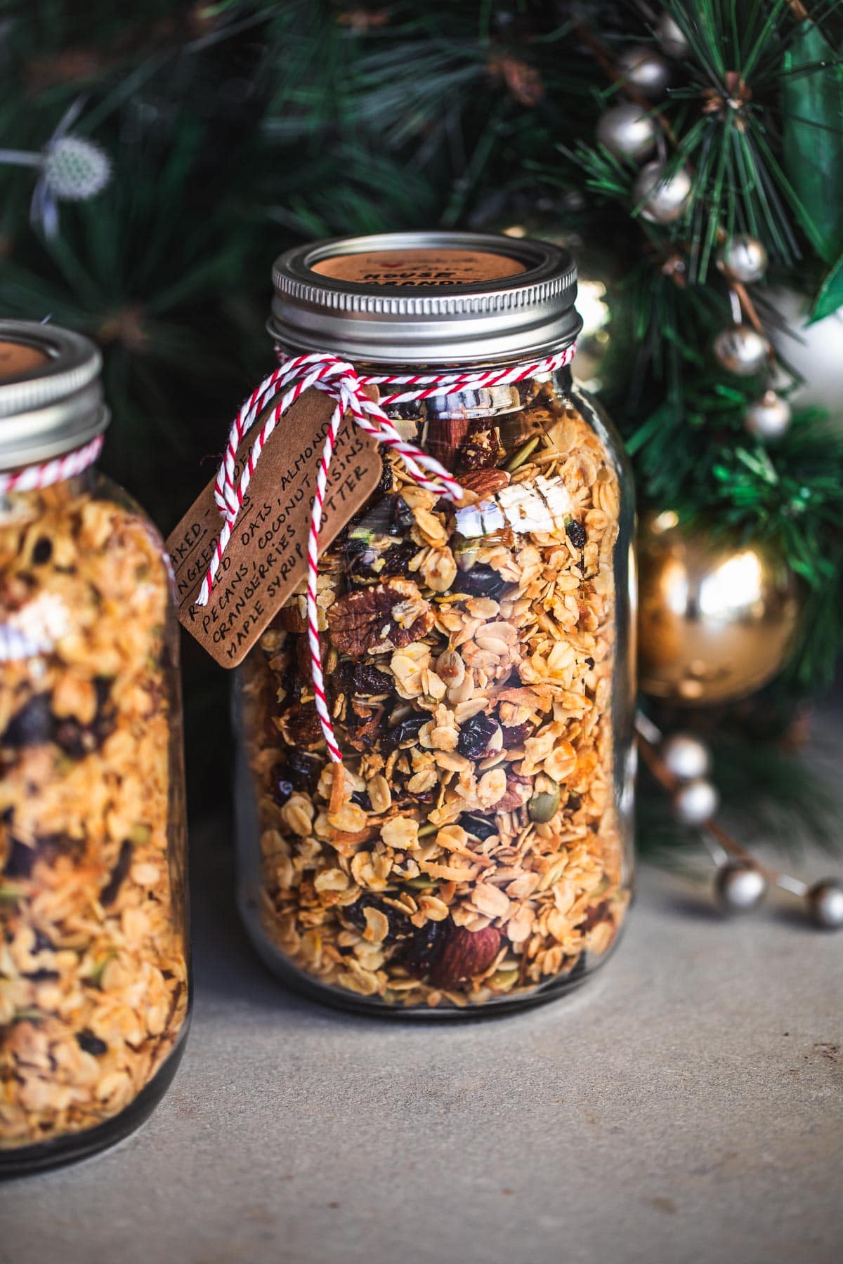 Homemade Granola stored in glass jars with twine and a handwritten label for gifting at Christmas.