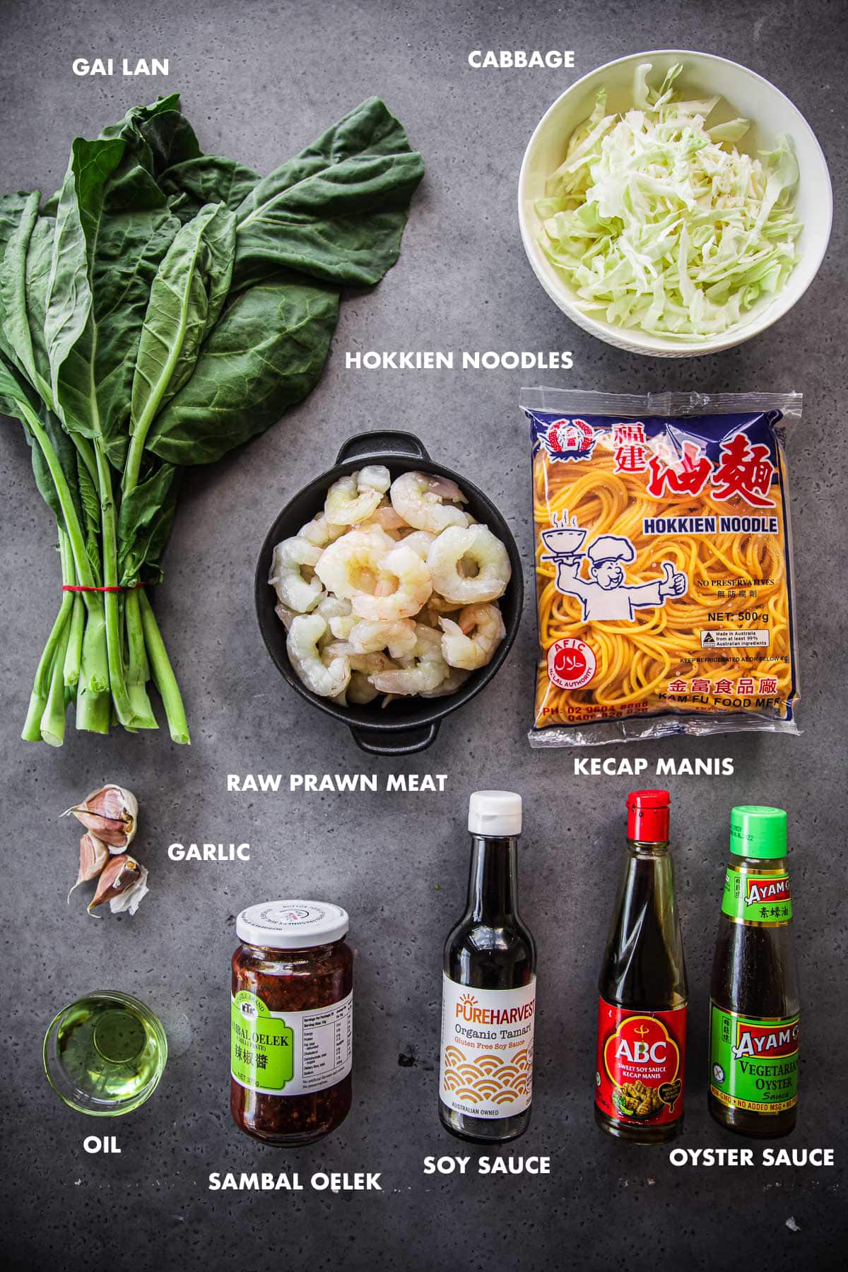 Prawn Hokkien Noodle Ingredients labeled - gai lan, cabbage, raw peeled prawns, hokkien noodles, garlic, oil, sambal oelek, kecap manis, oyster sauce and soy sauce.