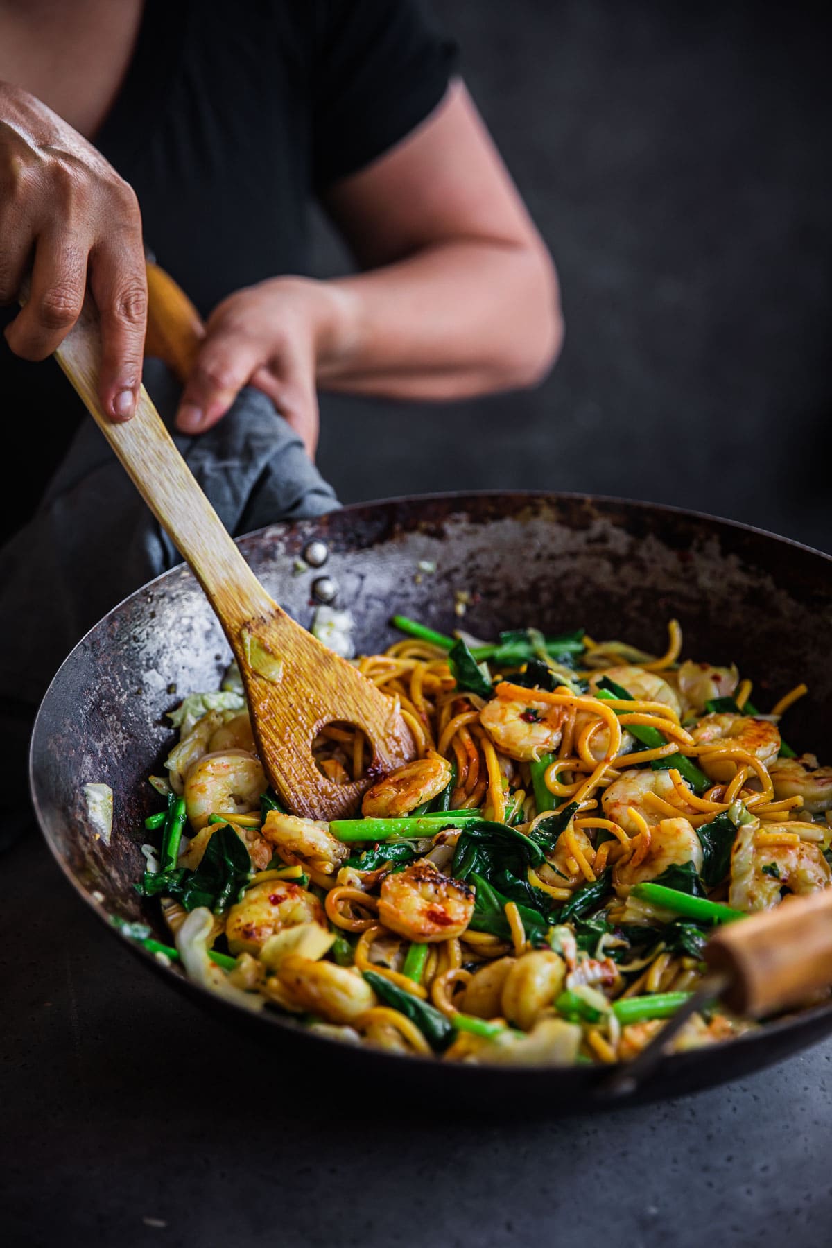 Prawn Hokkien Noodles being tossed in a wok with a wooden spatula.