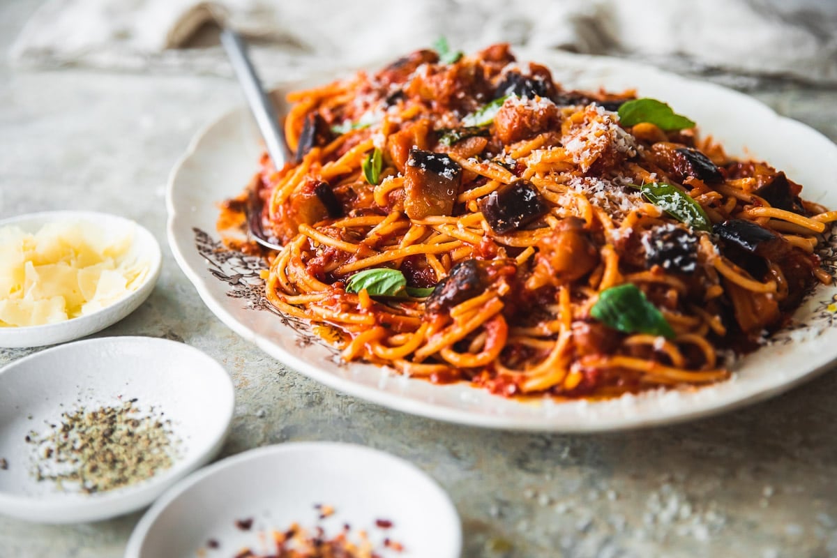 Pasta Alla Norma served in a vintage cream platter on a linen tablecloth.