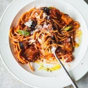 Pasta Alla Norma in a plate with a fork in the process of being eaten.