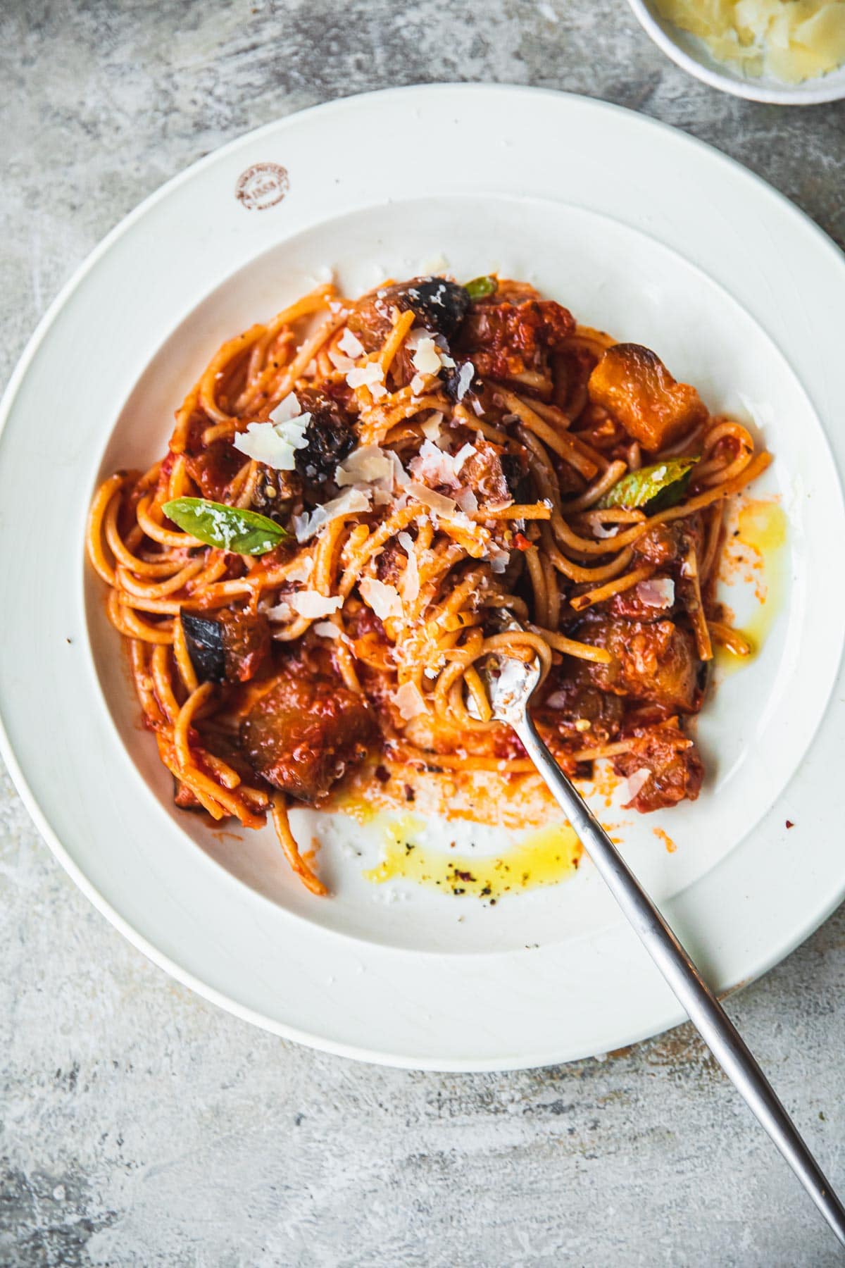 Pasta Alla Norma in a plate with a fork in the process of being eaten.