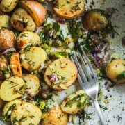 Roasted Dill Potato Salad in a bowl with zesty dressing and a fork.