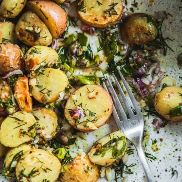 Roasted Dill Potato Salad in a bowl with zesty dressing and a fork.