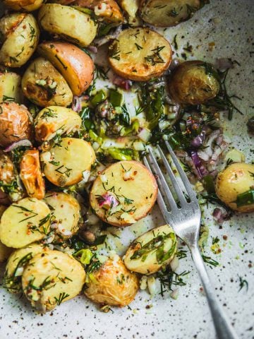 Roasted Dill Potato Salad in a bowl with zesty dressing and a fork.