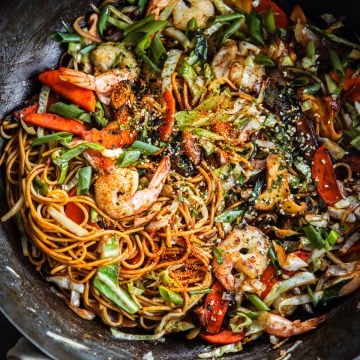 Prawn Yakisoba stir-fried in a wok with a tea towel around the wok handle.