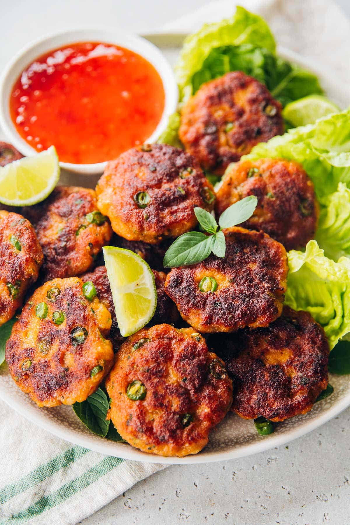 Delicious Thai Fish Cakes served with sweet chilli sauce, lime wedges and Cos lettuce leaves.