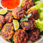 Thai Fish Cakes served on a platter with sweet chilli sauce, lime wedges and Cos lettuce.