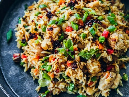 Chicken Fried Rice in a bowl with chopsticks and chilli oil for serving.