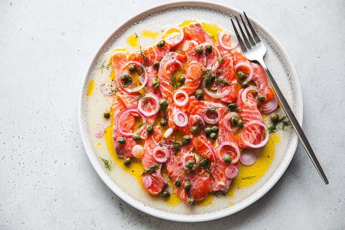 Salmon Crudo served in a flat serving platter with a fork resting on the side.