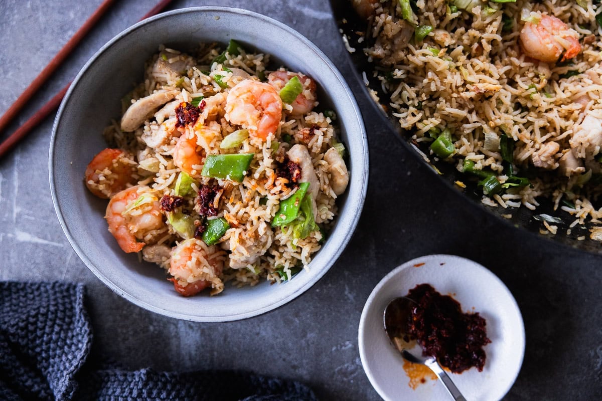 Garnish Shrimp And Chicken Fried Rice with chilli oil and serve in bowls.