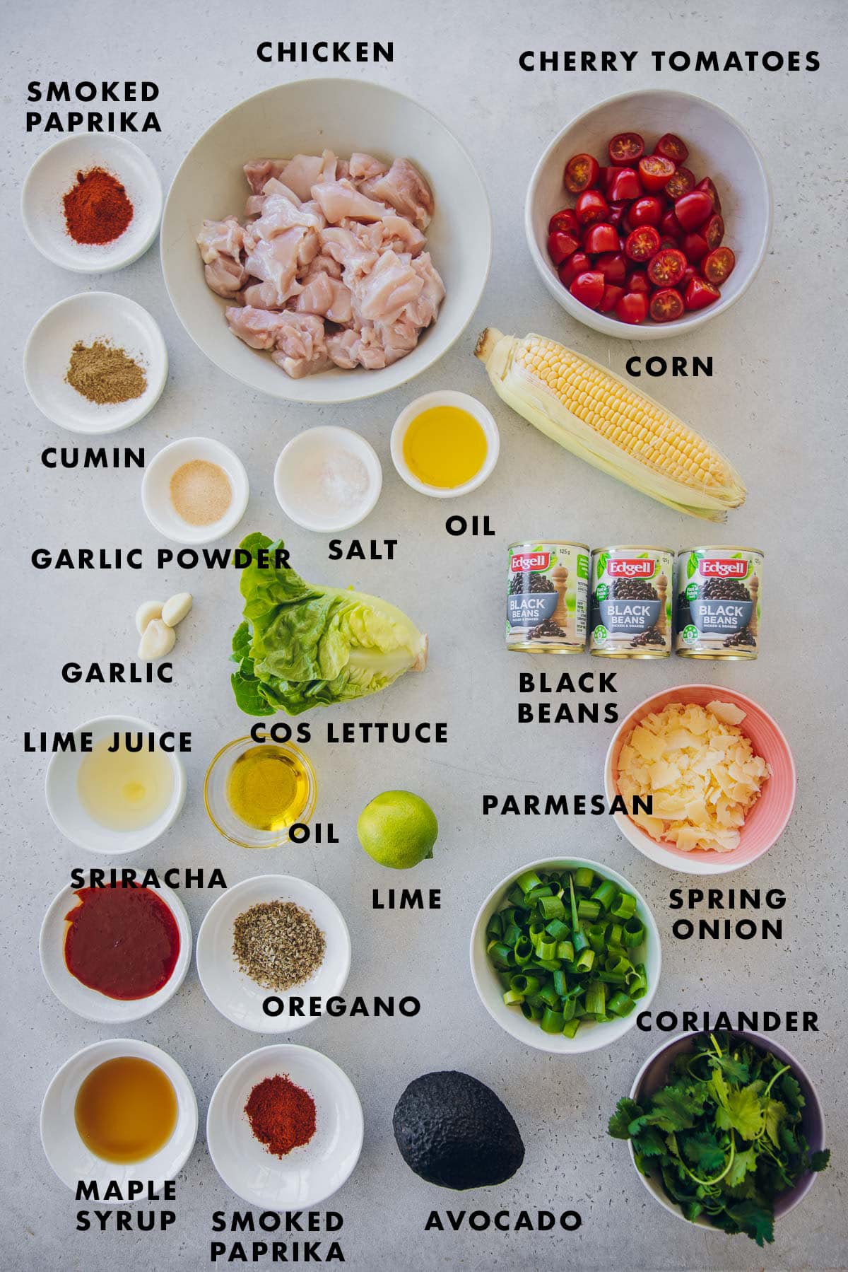 Mexican Chicken Salad Ingredients Labeled - chicken, avocado, cherry tomatoes, corn, black beans, cos lettuce, lime, garlic, coriander, parmesan, smoked paprika, cumin, oil, salt, oregano, sriracha, maple syrup.